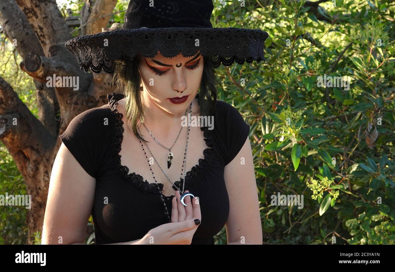 La ragazza teenage dimostra la sua fede Wiccan indossando vestiti neri e vari fascino come il cranio di un corvo e una luna d'argento Foto Stock