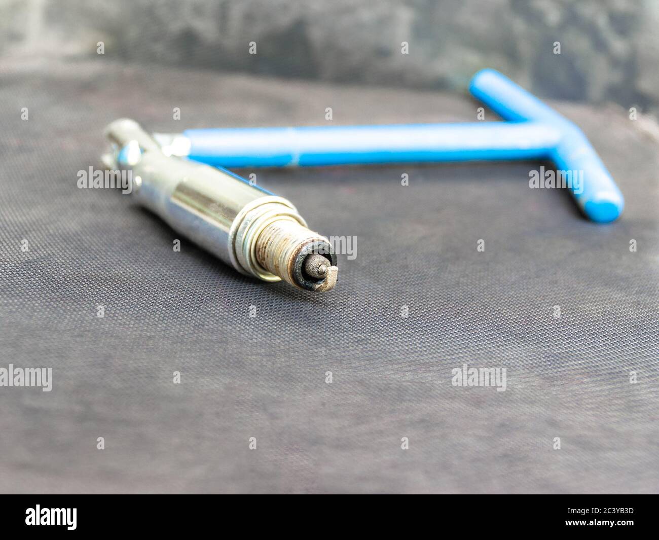 vecchia candela rivestita in carbonio con chiave blu incernierata per candele di accensione di un motore a combustione interna necessario alla stazione di servizio Foto Stock