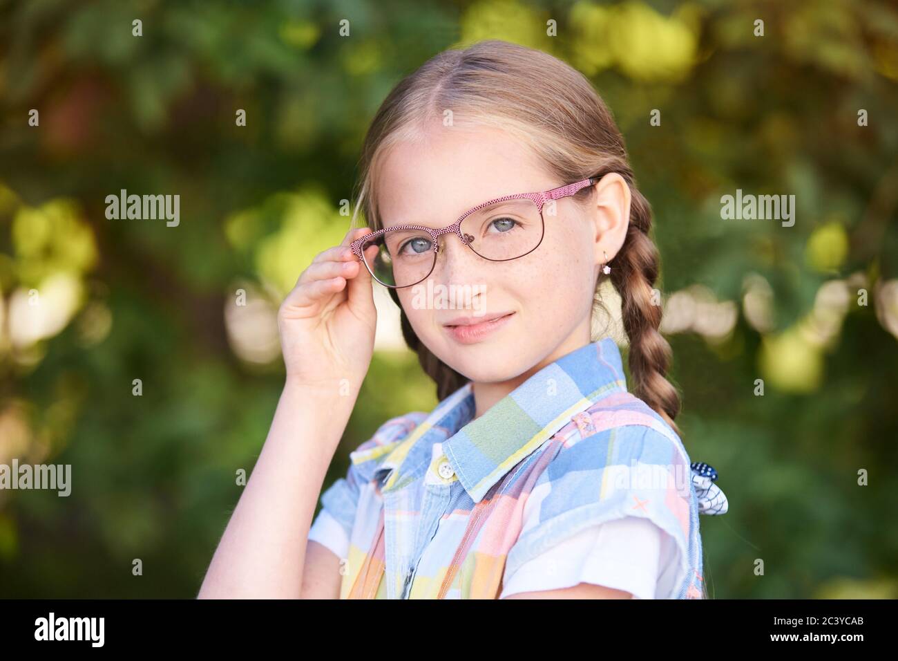 Scolari informali. Sorridi la bambina. Standind esterno con occhiali. Primo grado Foto Stock