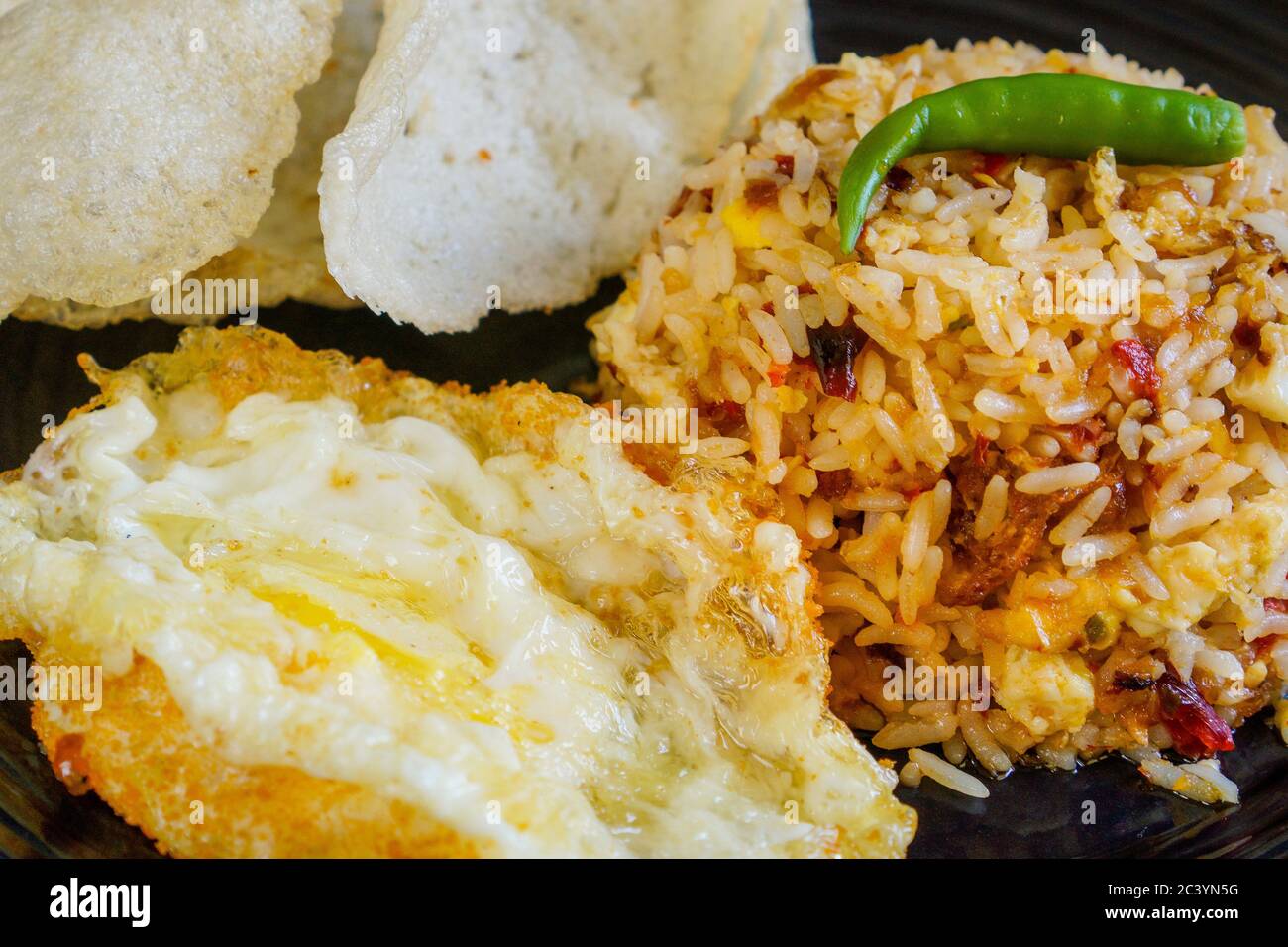 Riso fritto speziato con peperoncino essiccato con uova fritte e cracker di pesce. Foto Stock