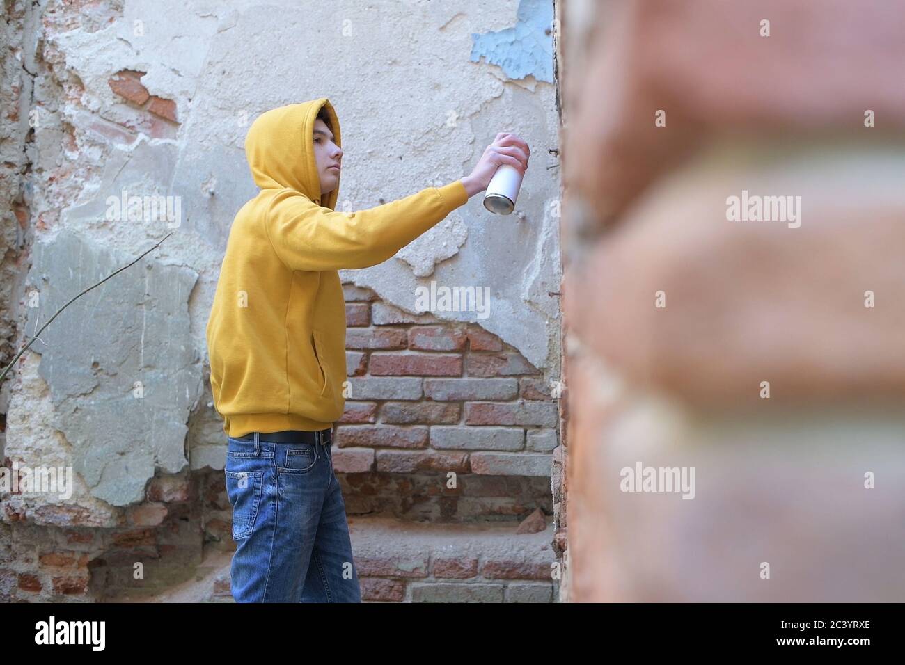 adolescente che dipinge una parete con una lattina di spruzzo di vernice Foto Stock