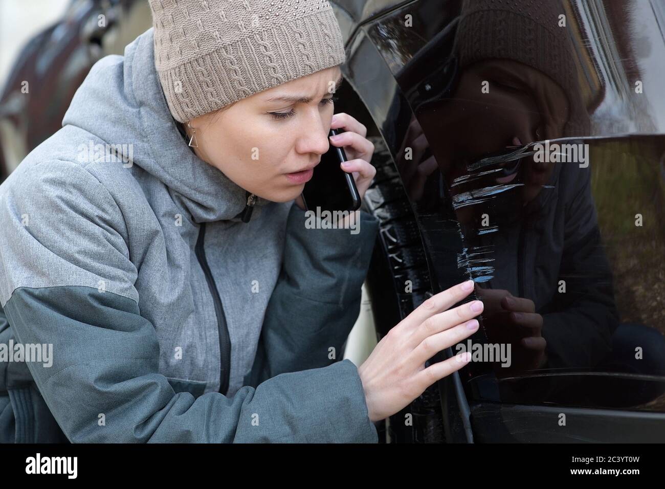 La ragazza nota graffi freschi sul paraurti del auto ed è sconvolto Foto Stock