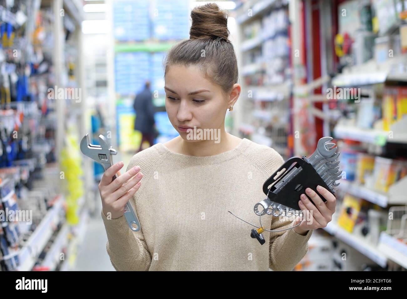 la giovane donna sceglie un'attrezzatura di lavoro in un negozio di hardware Foto Stock