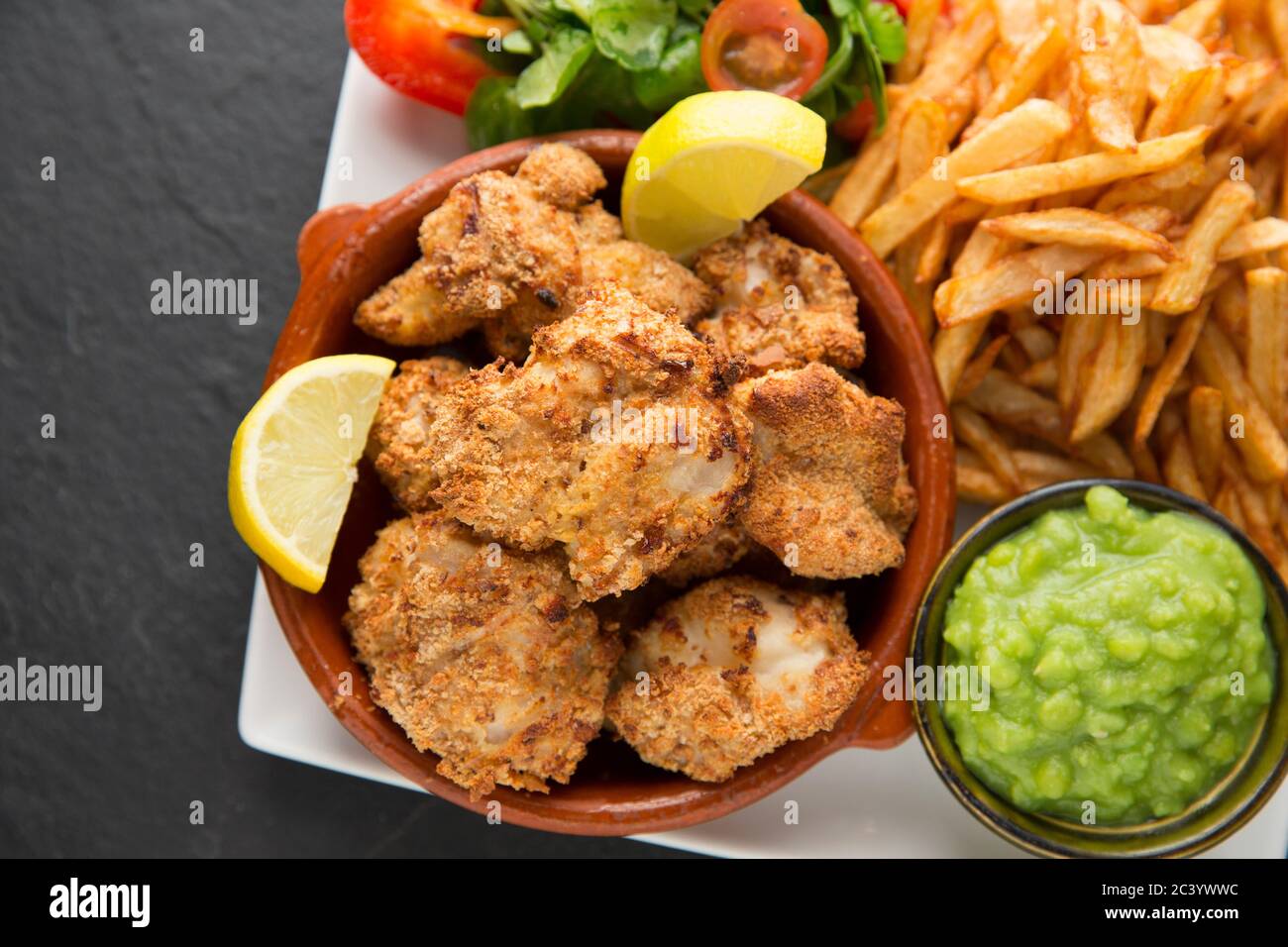 Guance a raggi, note anche come pomelli di skate, dai raggi di spina, Raja clavata, che sono state rivestite in pangrattato e cotto in forno. Servita con il c fatto in casa Foto Stock