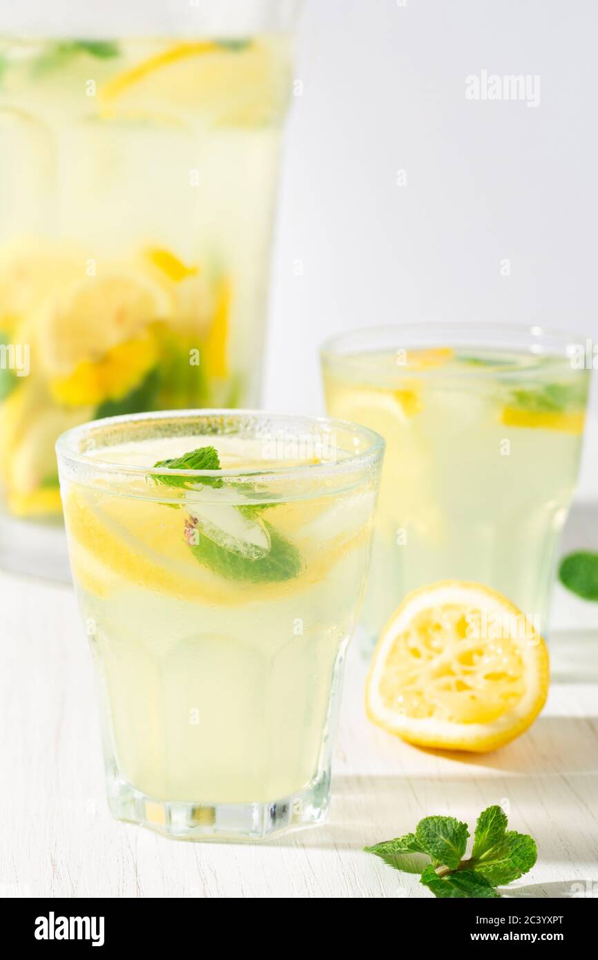 Due bicchieri e una caraffa di limonata sul tavolo bianco. Primo piano. Foto Stock