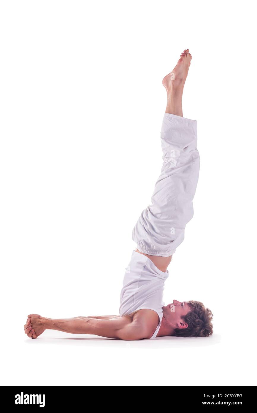 Uomo che pratica yoga preparazione per la testa in piedi posa senza mani su sfondo bianco. Niralamba shirshasana Foto Stock