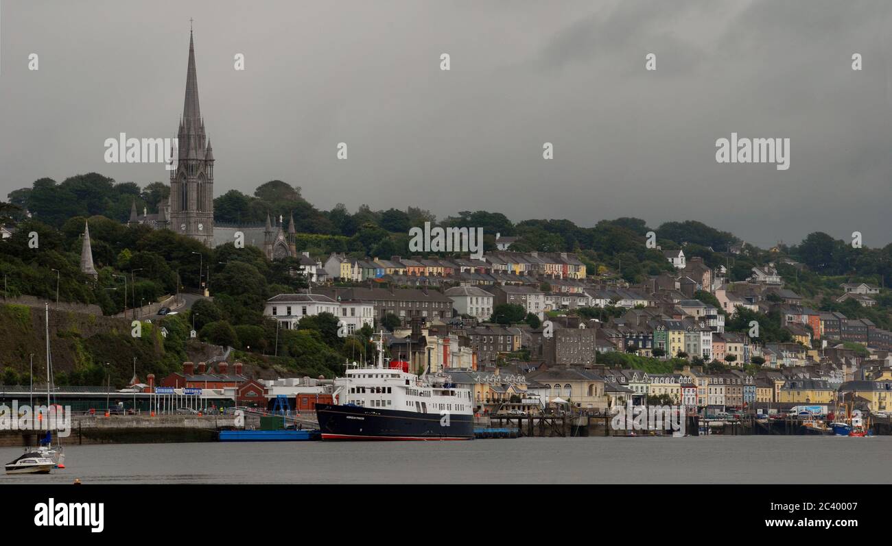 LA PRINCIPESSA EBRIDEA ormeggiava al terminal delle navi da crociera DI COBH con l'imponente Cattedrale di St COLMAN sulla collina che si affaccia su questa famosa città. Foto Stock