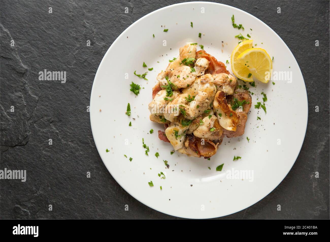 Guance a raggi, note anche come pomelli skate, da raggi di spina, Raja clavata, che sono state fritte con pancetta affumicata. Dorset Inghilterra GB Foto Stock