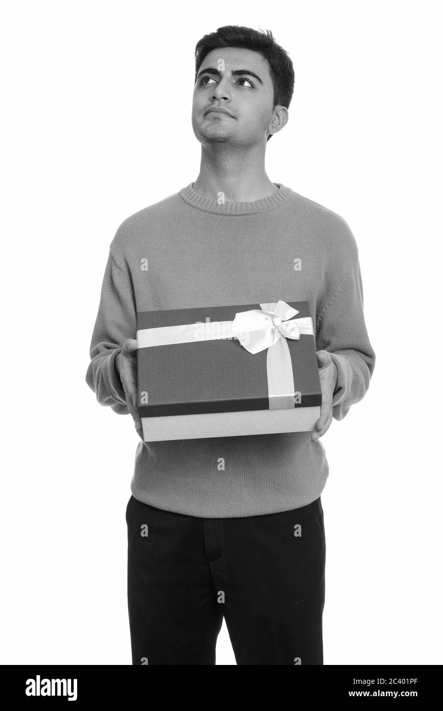 Bel giovane uomo persiano azienda confezione regalo mentre pensando pronto per il giorno di San Valentino Foto Stock