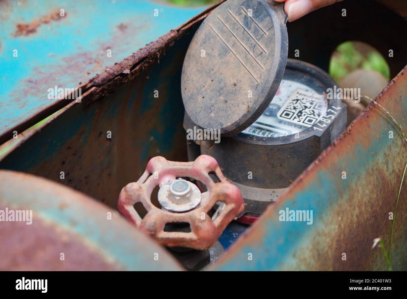 Controllo contatore acqua in una scatola di metallo arrugginito, fuoco selettivo Foto Stock