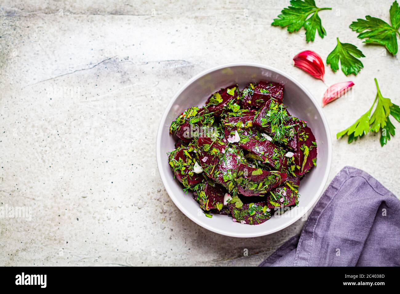 Insalata di barbabietole con aglio ed erbe in un recipiente grigio su sfondo chiaro. Foto Stock