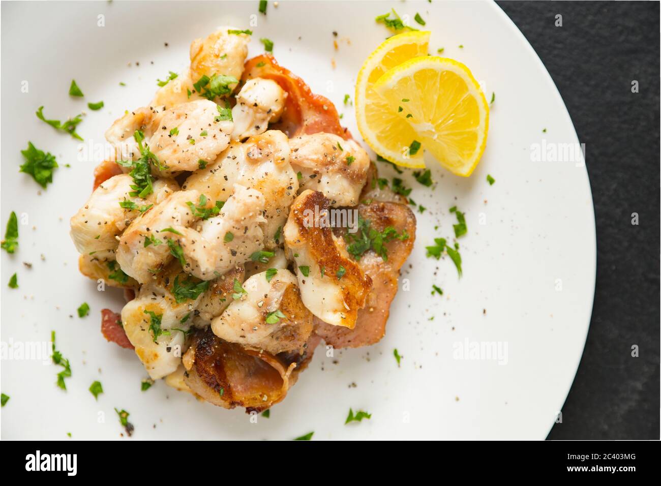 Guance a raggi, note anche come pomelli skate, da raggi di spina, Raja clavata, che sono state fritte con pancetta affumicata. Dorset Inghilterra GB Foto Stock