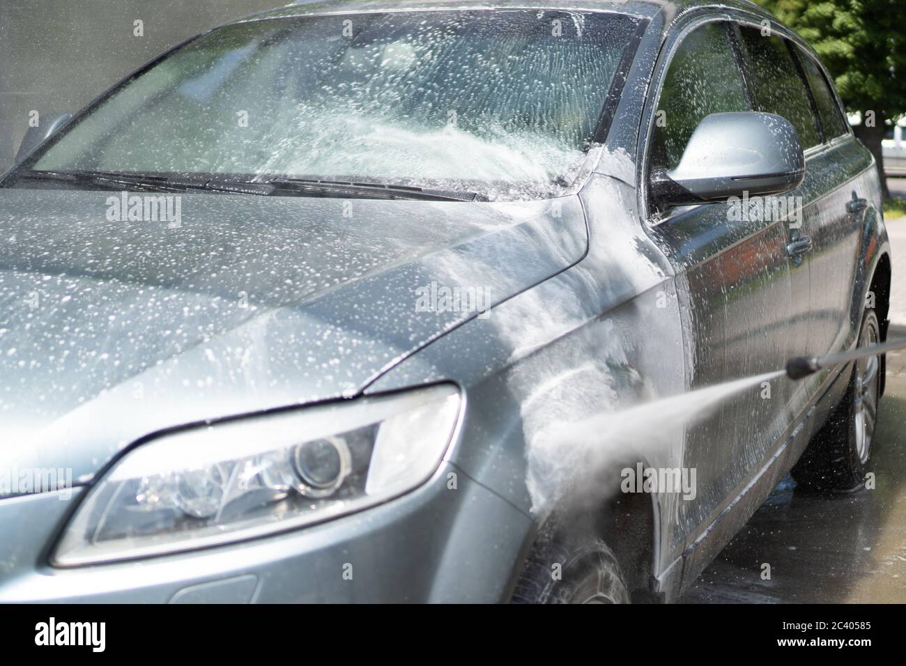 Lavaggio completo dell'auto presso il self service. Gocce d'acqua spruzzate da un'irroratrice che lava l'auto. Parabrezza. Schiuma bianca Foto Stock