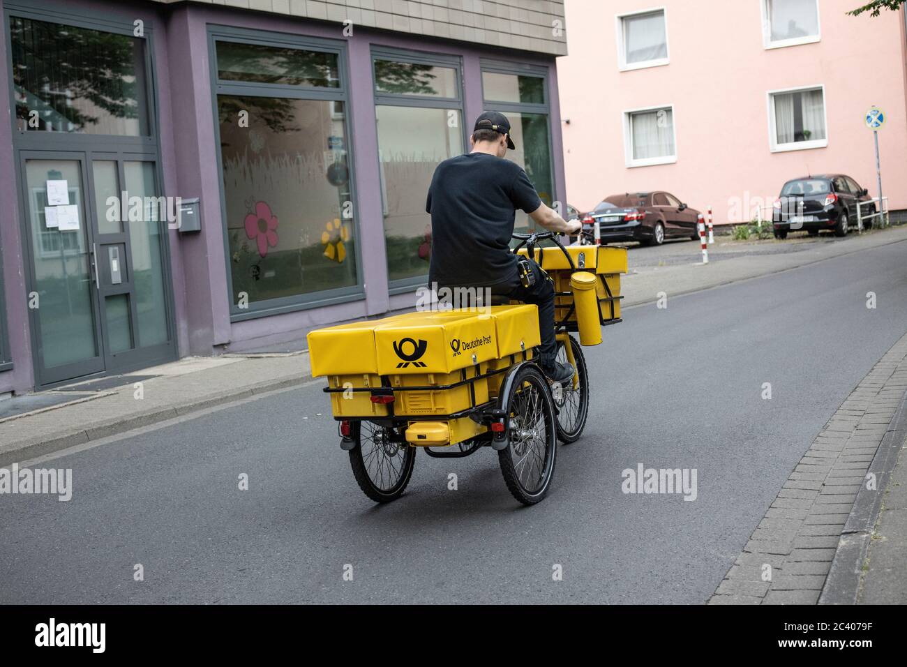 Il lavoratore postale che consegna il suo giro in bicicletta, Hannover, Germania Foto Stock