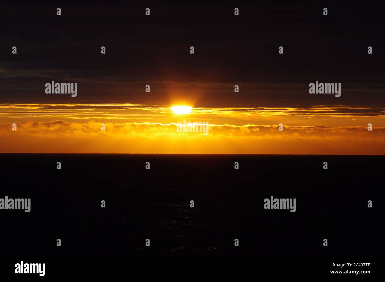 Tramonto su nuvole scure e mare, fascio luminoso di orizzonte tra nuvole scure e mare, sequenza di immagini di tramonto che emergono dal cielo scuro Foto Stock