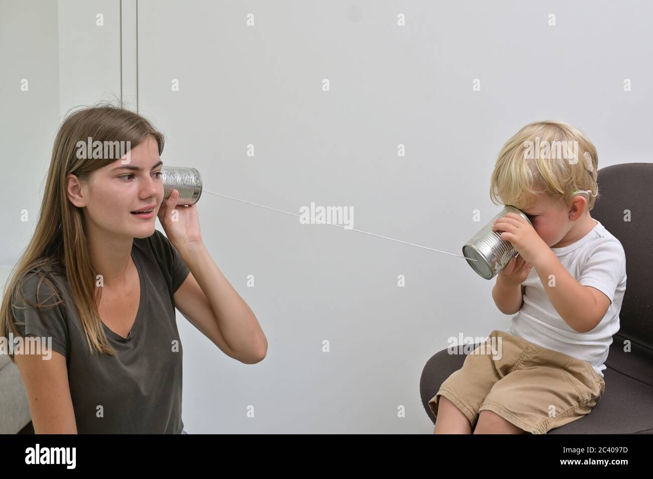 Un ragazzo con impianti Cochlear giocando Tin CAN Phone Foto Stock