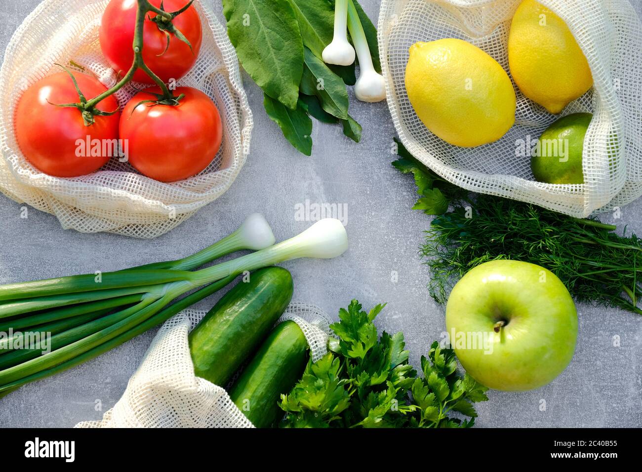 Concetto di shopping senza sprechi. Verdure fresche e frutta in sacchetti di cotone eco-friendly su tavola di pietra. Vista dall'alto, pomodori a piatto, cetrioli, limoni, gr Foto Stock