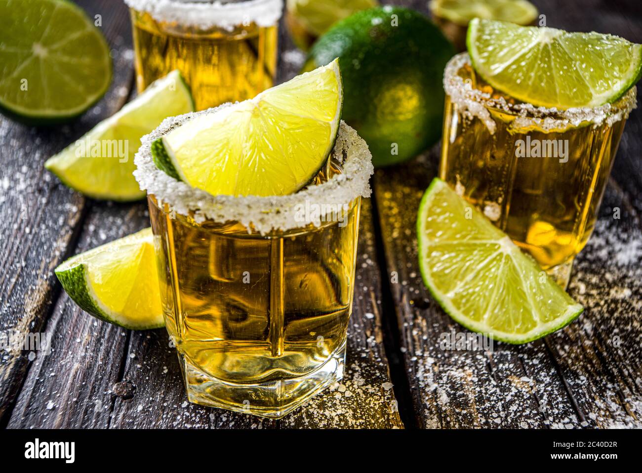Tequila Golden shot. Tre bicchieri da tequila con fette di sale e lime, su sfondo di legno spazio copia Foto Stock