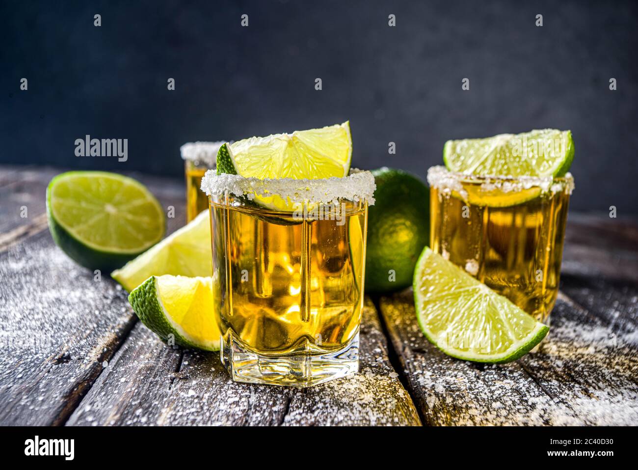 Tequila Golden shot. Tre bicchieri da tequila con fette di sale e lime, su sfondo di legno spazio copia Foto Stock