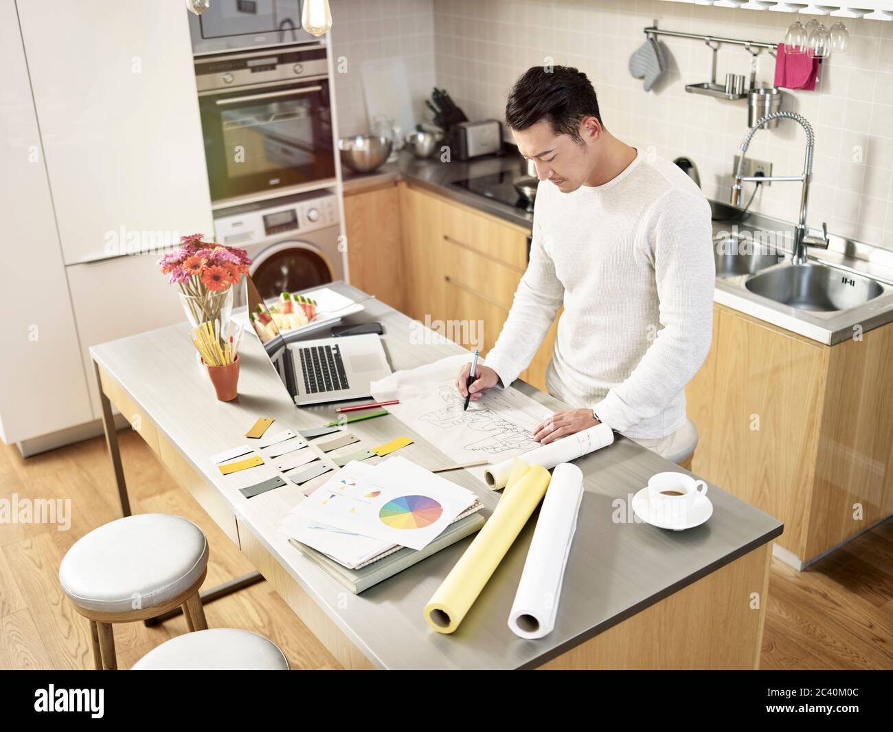 designer freelance asiatico che lavora da casa disegno un disegno su carta da disegno Foto Stock