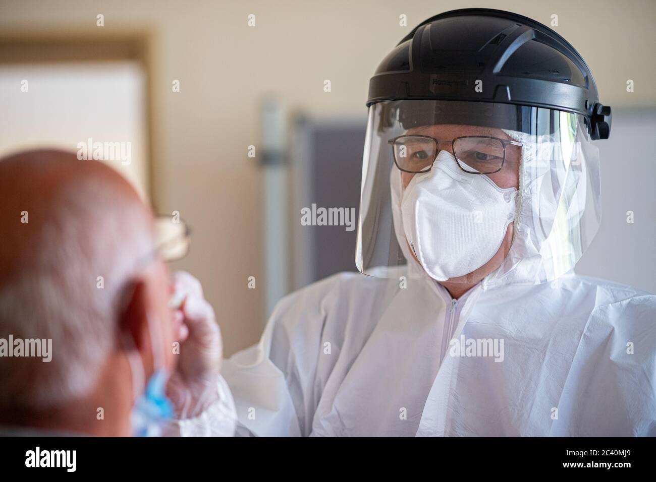 23 giugno 2020, Nord Reno-Westfalia, Gütersloh: Hendrik ohn, un medico dell'Associazione Nord Reno-Westfalia dei medici legali di assicurazione sanitaria, conduce un test gratuito di coronavirus su un uomo presso il college professionale Carl Miele. In relazione a quella che attualmente è la più grande epidemia di coronavirus locale della Germania nella fabbrica di carne von Tönnies nel distretto della Westfalia orientale di Gütersloh, il coronavirus è stato rilevato in più di 1500 dipendenti. Il distretto supera quindi il limite concordato dai governi federale e statale. Foto: Guido Kirchner/dpa Foto Stock