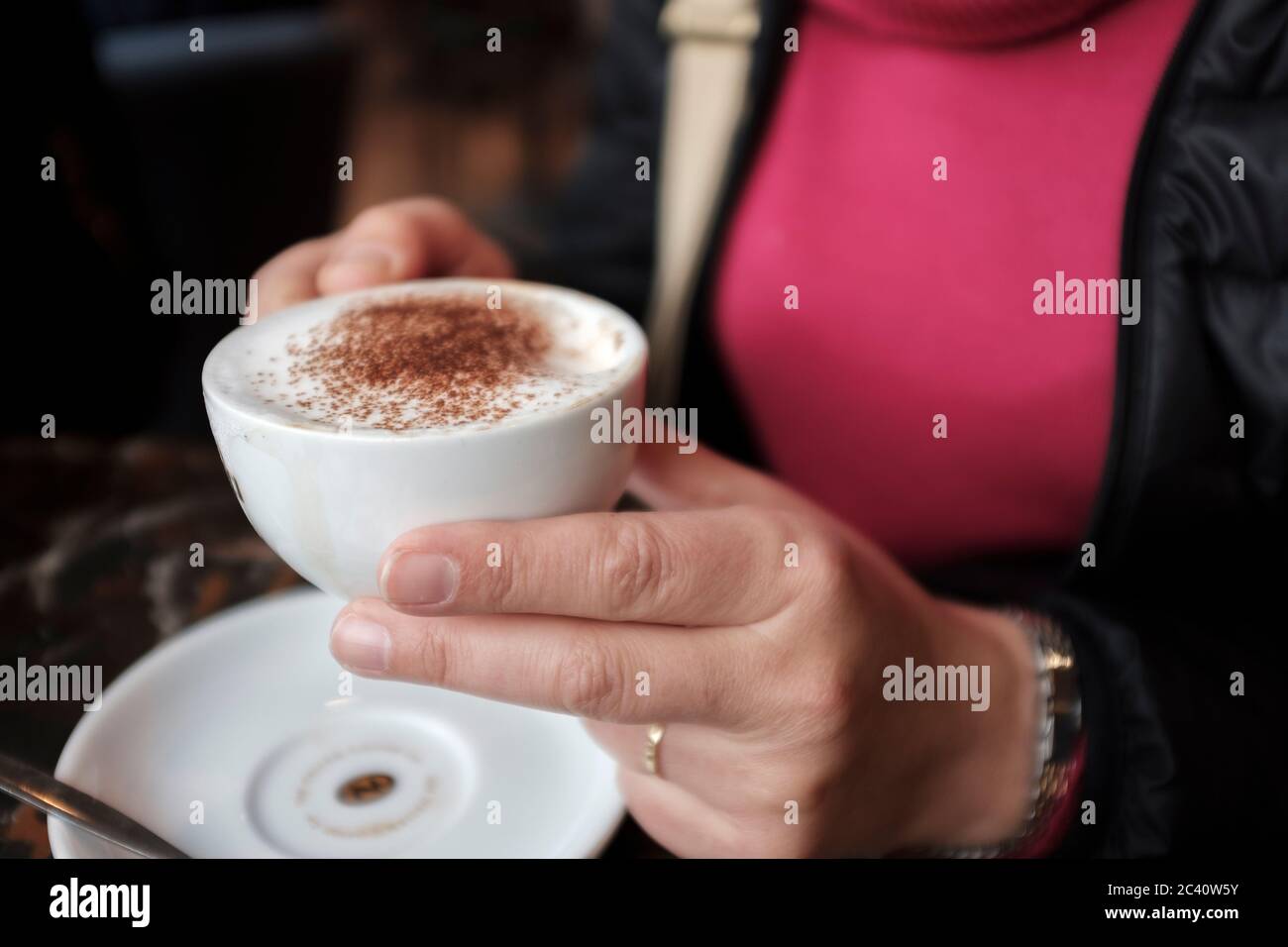 Primo piano di una donna che si sta gustando una tazza di cappuccino in una caffetteria Foto Stock