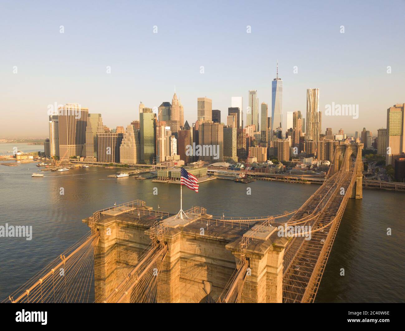 Vista aerea del ponte di Brookyln con la bandiera americana e lo skyline di Manhattan sullo sfondo a Daylight Foto Stock