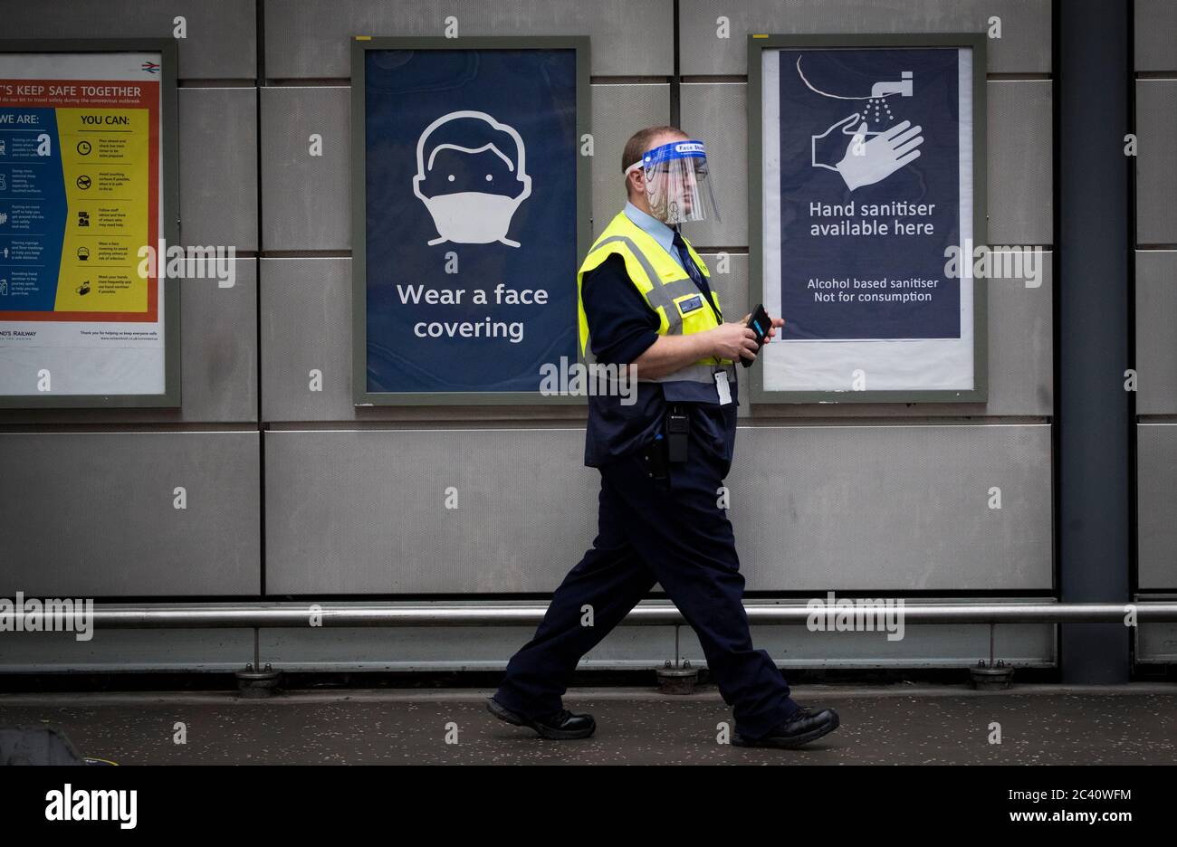 Un membro del personale indossa uno scudo protettivo all'interno della Waverley Station, Edimburgo, mentre la Scozia si sposta nella seconda fase del suo piano in quattro fasi per uscire dal blocco. Foto Stock