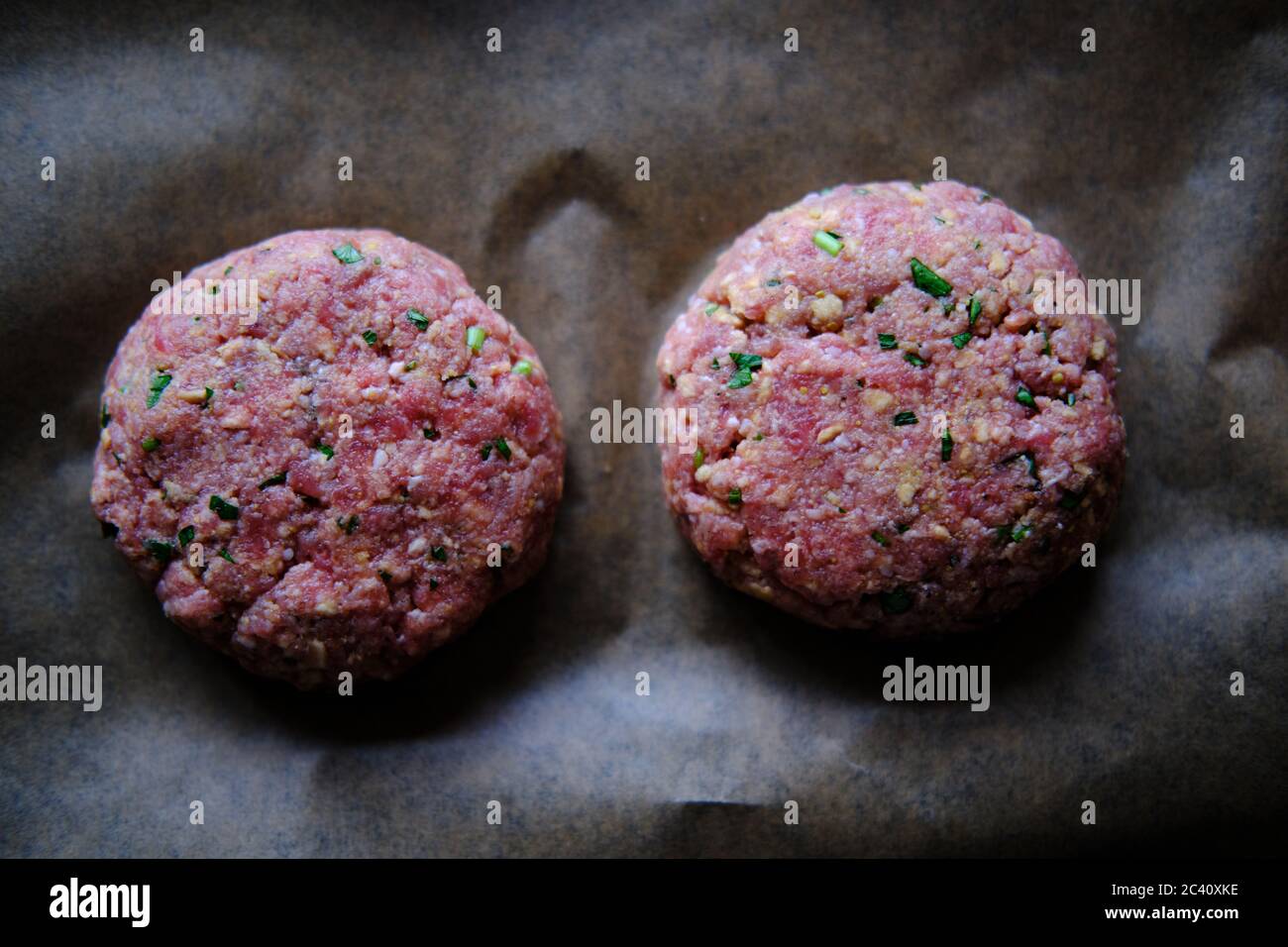 Preparazione di polpettine di hamburger, carne di hamburger cruda. Concetto per la produzione di hamburger fatti in casa. Foto Stock