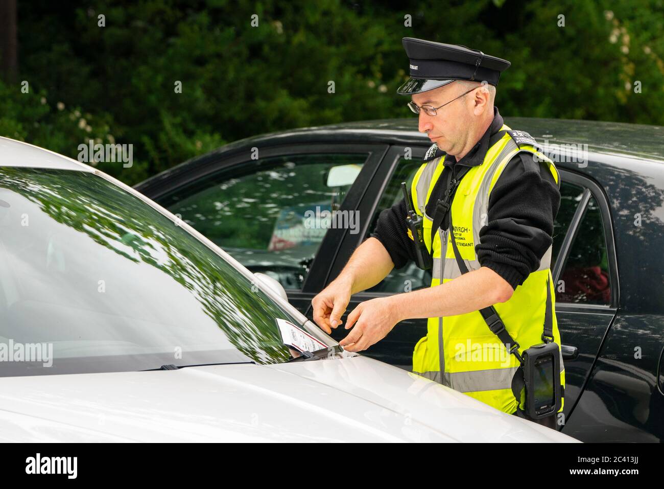 Edimburgo, Scozia, Regno Unito. 23 giugno 2020. L'addetto al parcheggio dà un biglietto per l'auto parcheggiata illegalmente a Edimburgo. A partire dal 22 giugno, il consiglio comunale di Edimburgo ha iniziato a rilasciare i biglietti per il parcheggio a seguito di una sospensione durante la pandemia del coronavirus. Iain Masterton/Alamy Live News Foto Stock