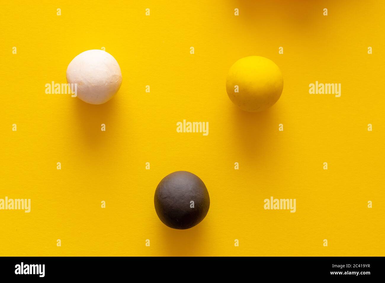 Palline bianche e gialle nere che si levano insieme su uno sfondo giallo. Rappresentando le tre principali razze umane, concetti di razzismo, questioni sociali e. Foto Stock