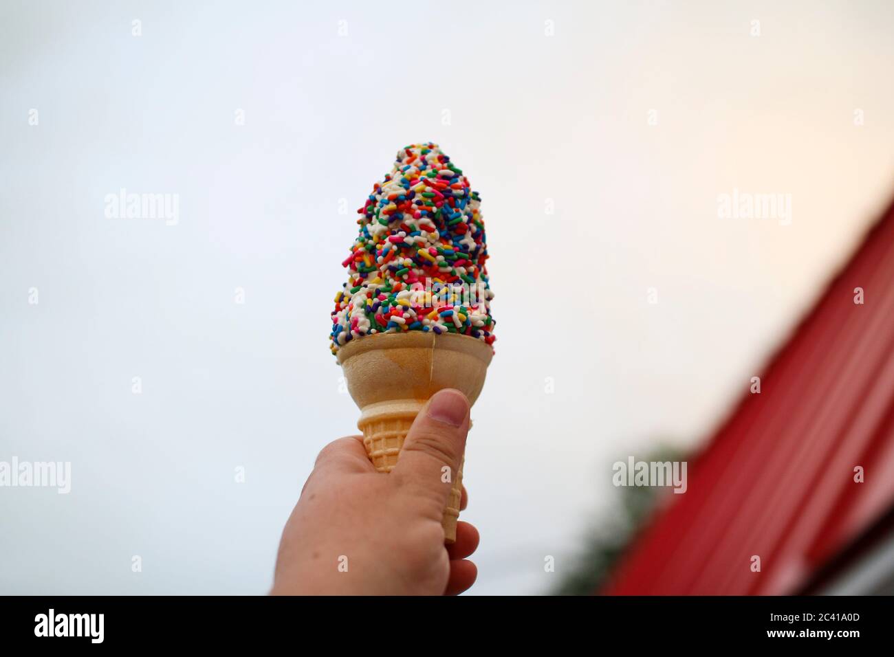 Un cono di gelato con spruzzare in mano Foto Stock