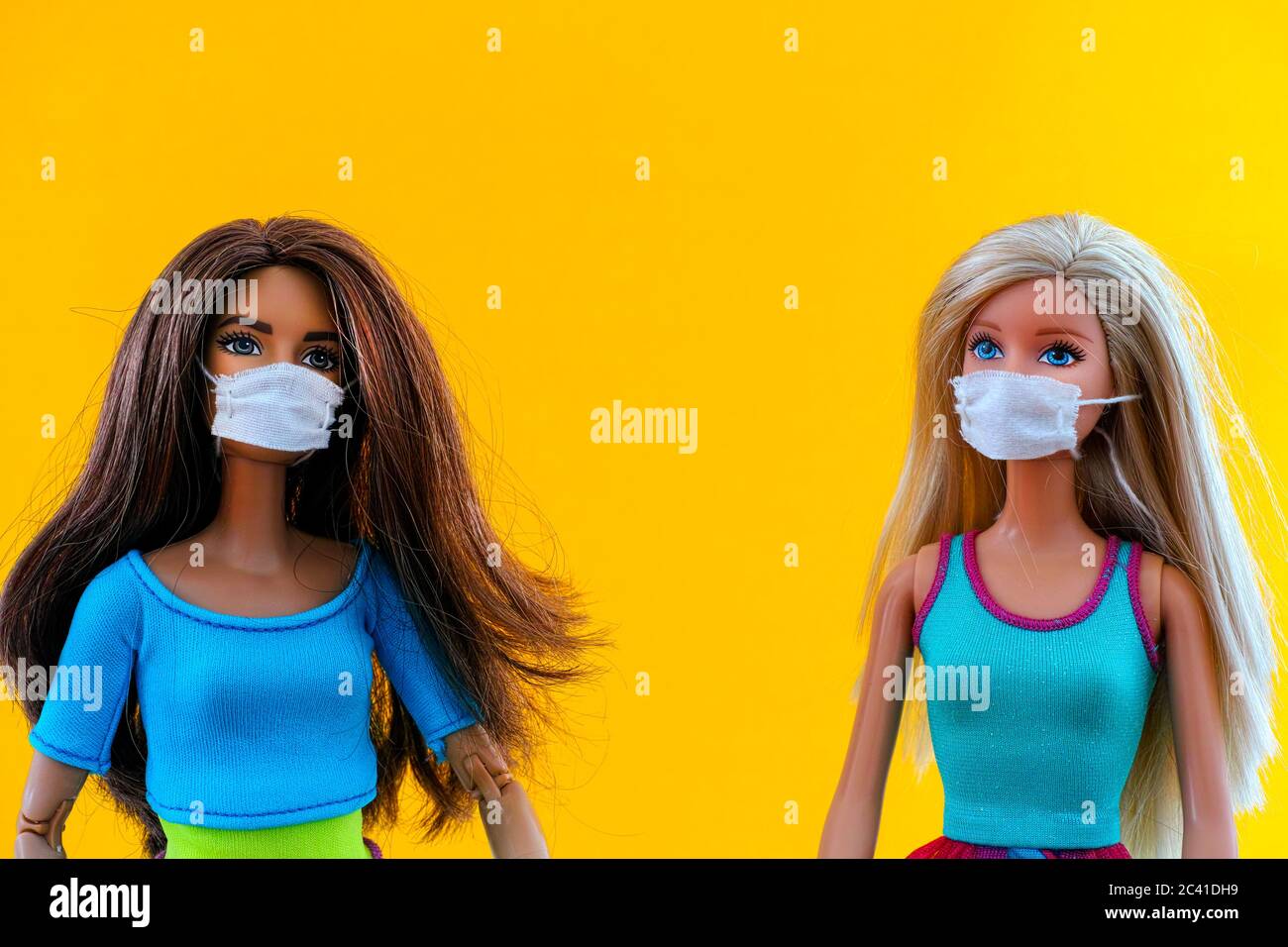 Tambov, Federazione Russa - 12 Giugno 2020 due bambole Barbie con maschere mediche su sfondo giallo. Scatto in studio. Foto Stock