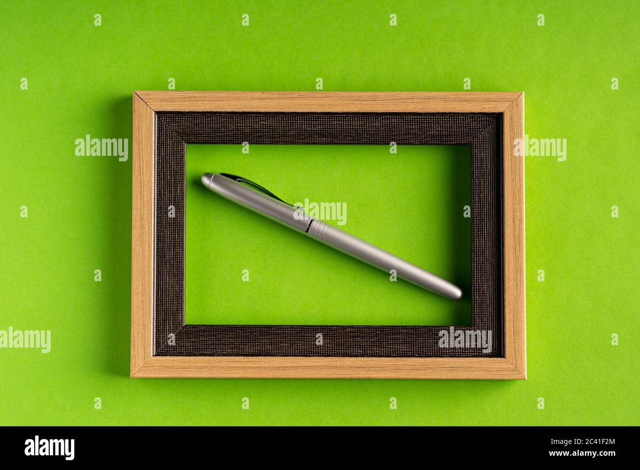 Elegante penna in argento e cornice vuota su sfondo verde Foto Stock