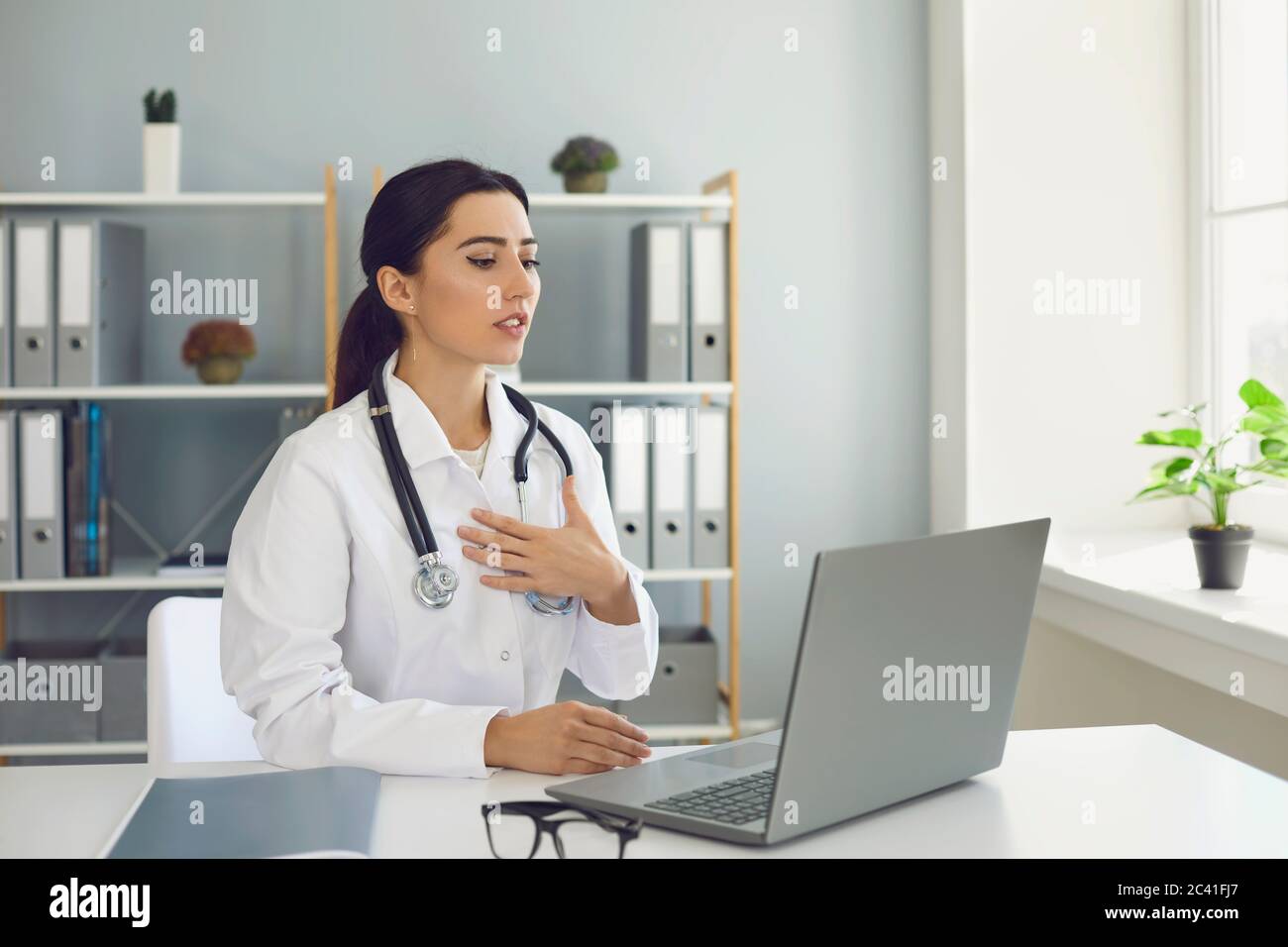 Consultazione medica online. Dottore donna che parla con la paziente sul computer portatile in clinica. Medico che effettua una videochiamata con il cliente Foto Stock