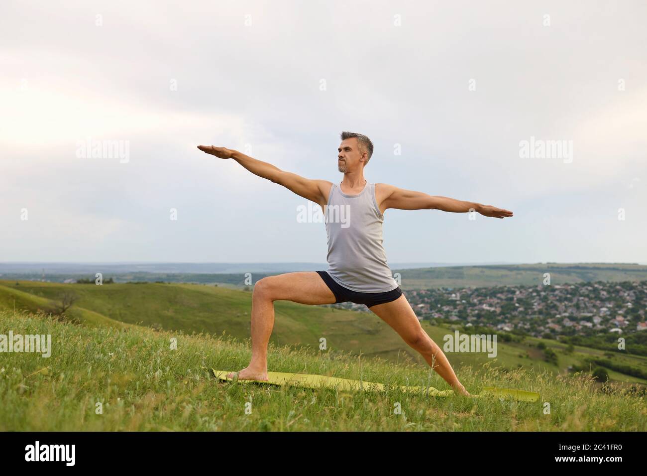 Uomo maturo che fa yoga esercizio Valence su erba verde in natura. Foto Stock