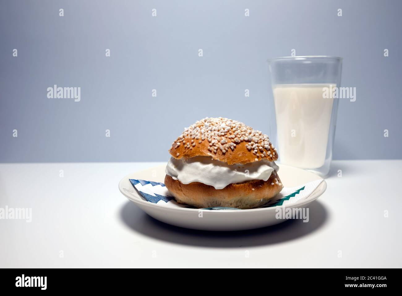 Un tradizionale fiasche scandinavo shrovetide con panna montata, zucchero perlato sulla parte superiore e un bicchiere di latte su tavola bianca. Foto Stock