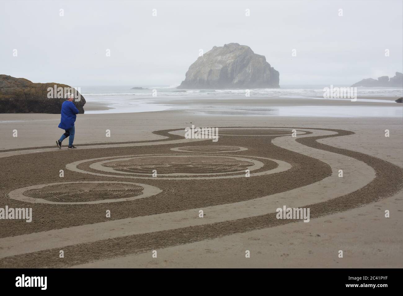 Una donna che cammina un cerchio nel labirinto di sabbia a Face Rock Beach a Bandon, Oregon, Stati Uniti. Foto Stock