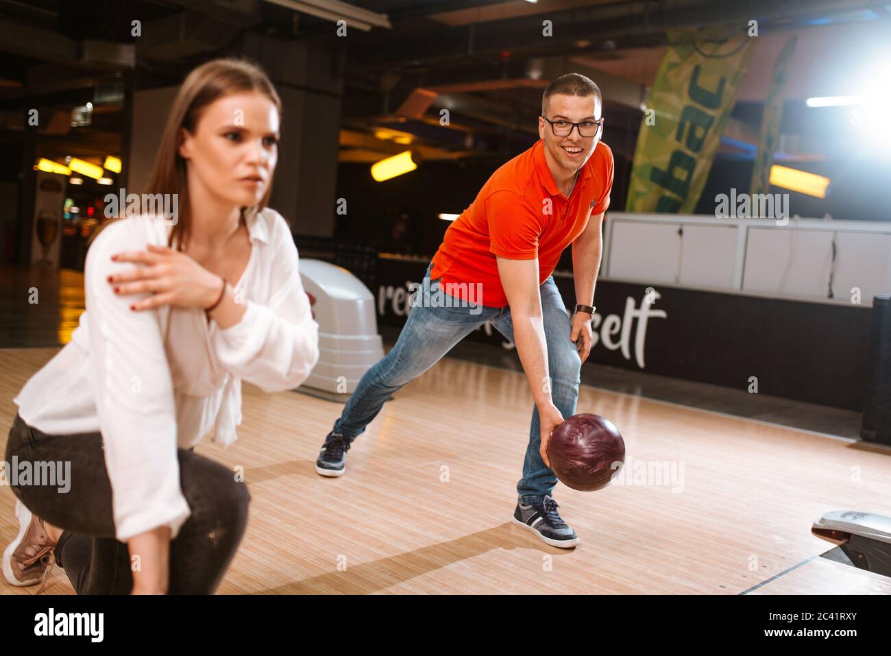 Una bella coppia caucasica che lancia palle sulla pista da bowling. Fidanzata e ragazza al bowling club Foto Stock