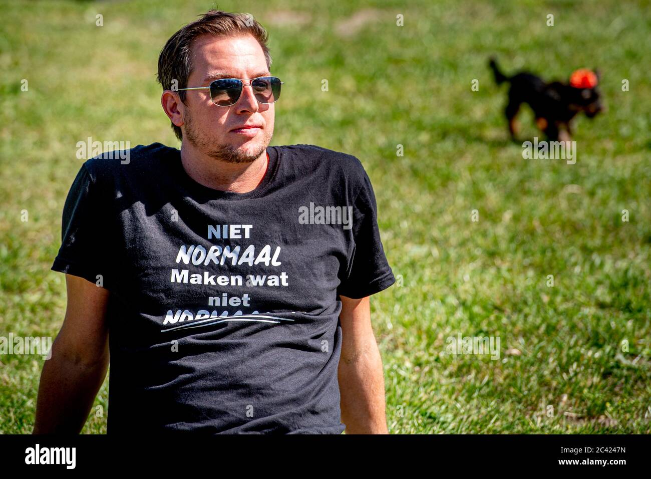 Un manifestante è visto seduto a guardare la protesta. Manifestanti sul campo di Malieveld nel centro della città di l'Aia si sono riuniti durante una protesta relativa al settore della ristorazione e dell'intrattenimento. Gli attivisti credono che il governo dovrebbe allentare le misure di restrizione del coronavirus e lasciarli tornare al lavoro. Foto Stock