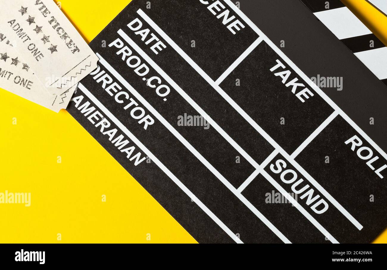 Singolo, nero, clapper o clapper-board con biglietti per cinema piatto, vista dall'alto su sfondo giallo o arancione Foto Stock