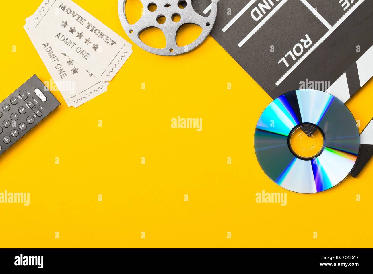 Clapper o clapper-board singoli, neri, aperti con DVD movie disc, film reel, telecomando e biglietti per cinema su sfondo giallo o arancione Foto Stock