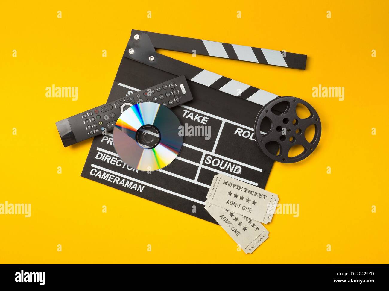 Clapper o clapper-board singoli, neri, aperti con DVD movie disc, film reel, telecomando e biglietti per cinema su sfondo giallo o arancione Foto Stock