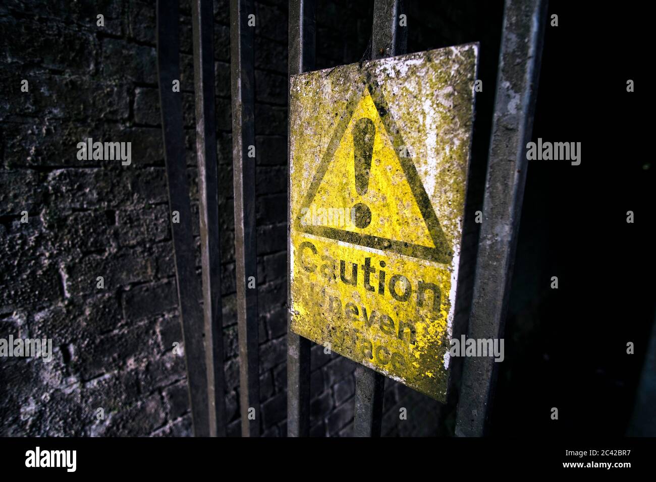 Attenzione, cartello con la superficie irregolare all'ingresso del tunnel Oxendon sulla Brampton Valley Way, una linea ferroviaria in disuso, ora un sentiero pubblico e pedalare Foto Stock