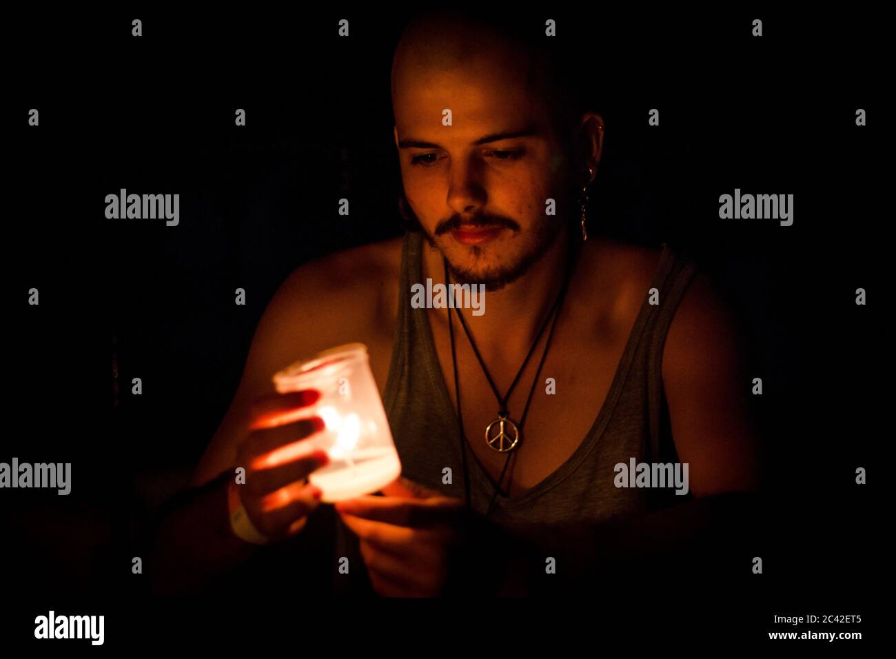 Ragazzo con una candela nelle mani nelle tenebre. Foto Stock