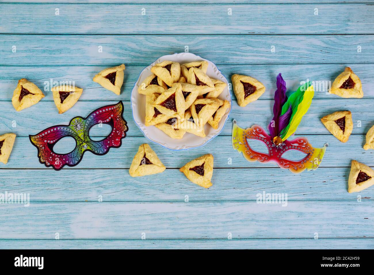 Maschera Purim e biscotti triangolari su sfondo bianco di legno. Foto Stock