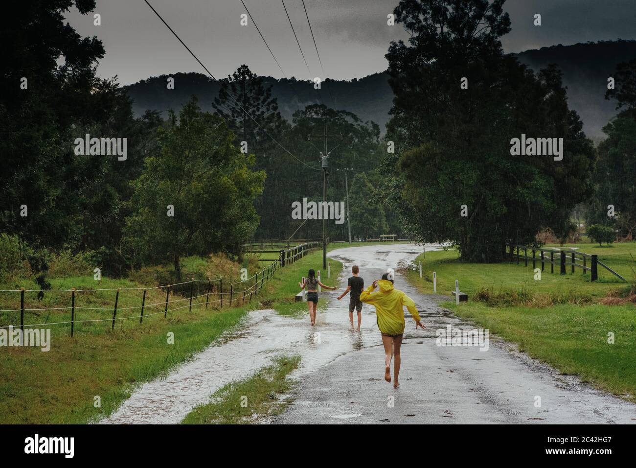 Due ragazze e un ragazzo che giocano sotto la pioggia dopo un ciclone Foto Stock