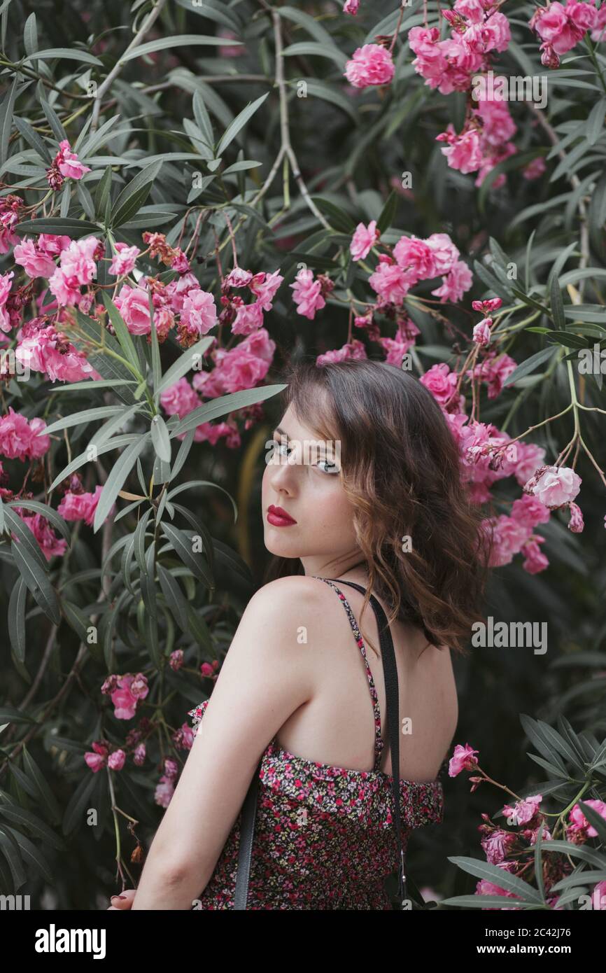 Ritratto di giovane donna in piedi vicino oleandro fiore Foto Stock