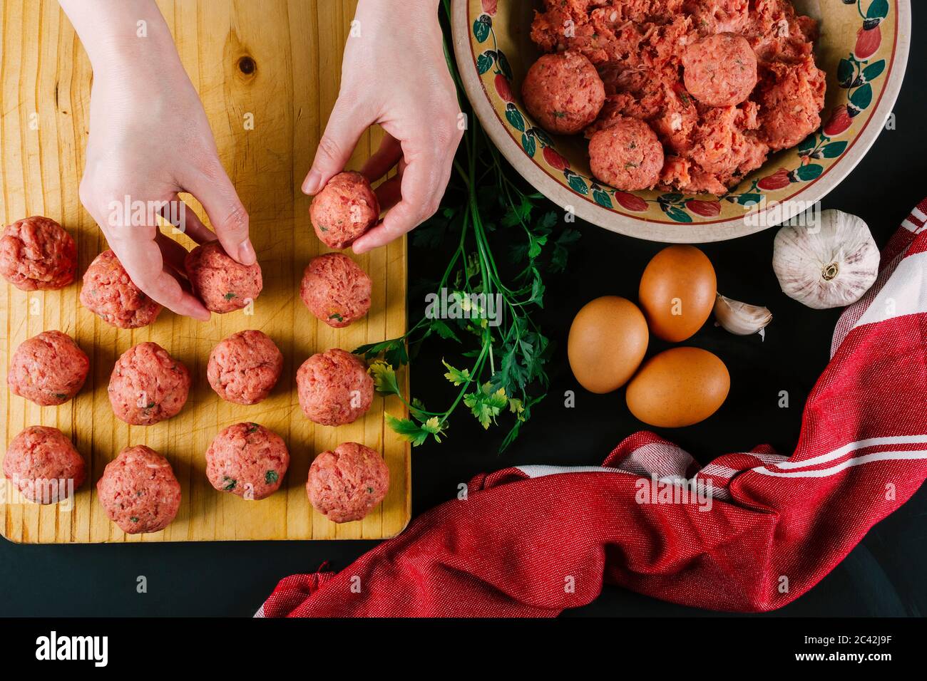 Donna produce polpette fatte in casa con carne macinata condita con spezie varie per il sapore. Foto Stock