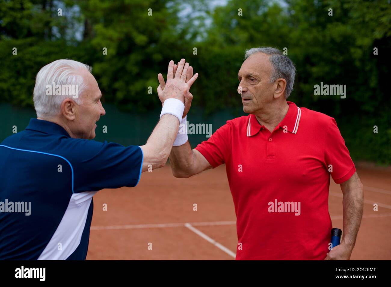 Due uomini più anziani sul campo da tennis si aggrappano Foto Stock